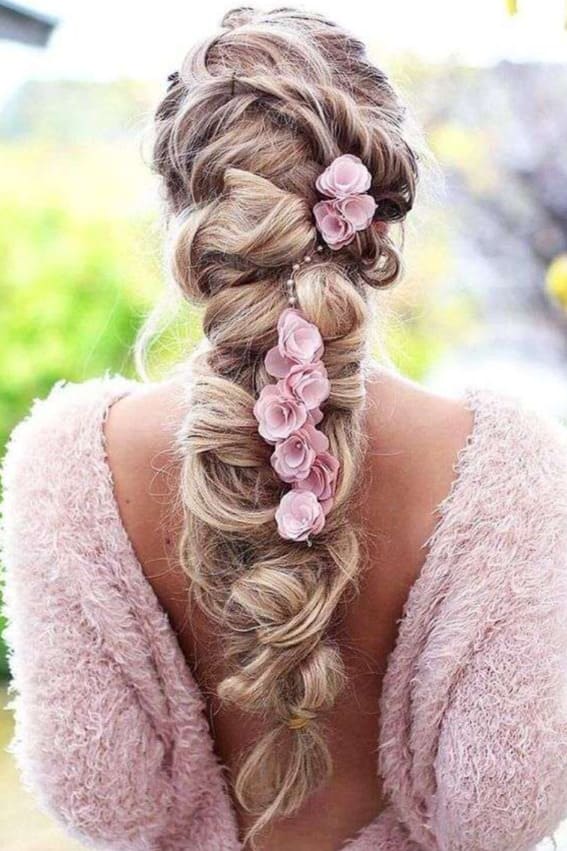 A girl who has romantic braids of boho decorated in pink accents are the perfect for a wedding party.