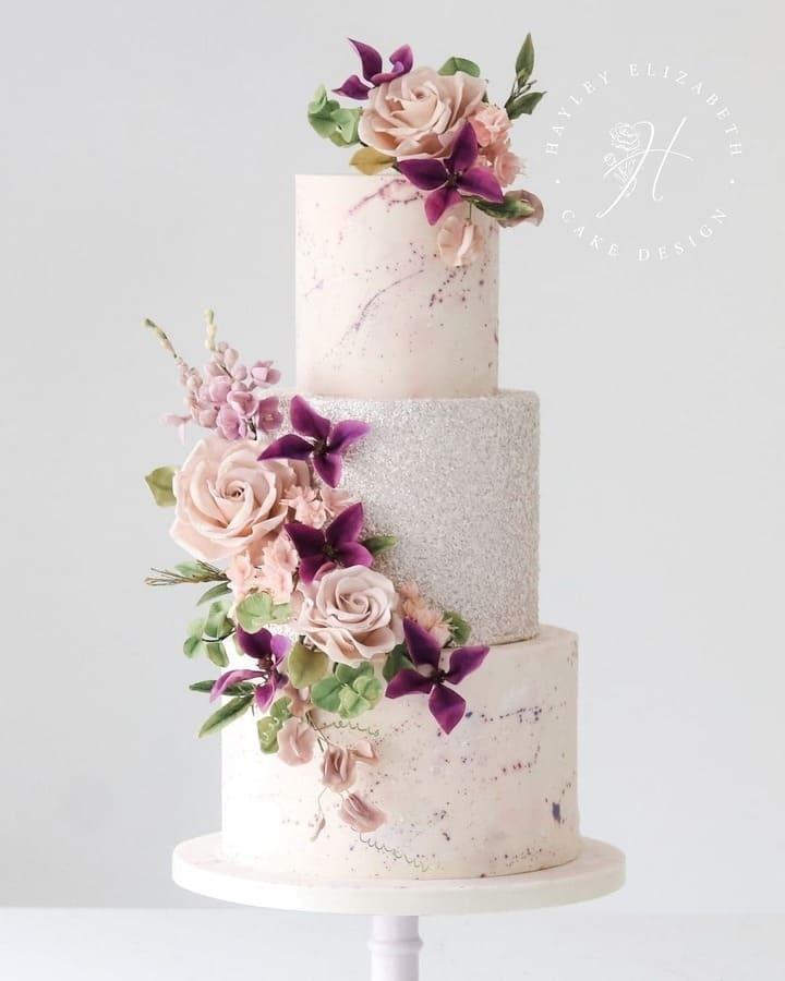 Three-tiered blush and silver wedding cake with sugar florals and subtle purple accents