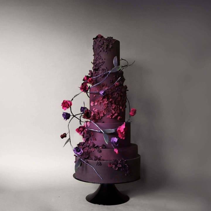 Five-tiered deep plum wedding cake with sculpted flowers and climbing sugar vines