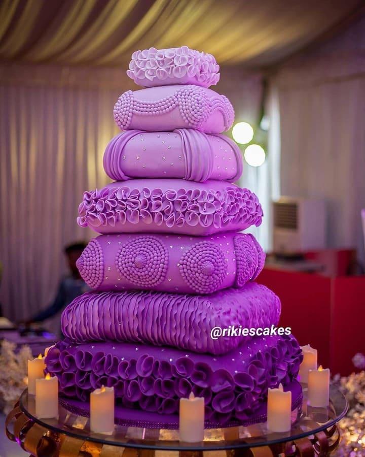 Seven-tiered monochromatic purple wedding cake sculpted like stacked decorative pillows